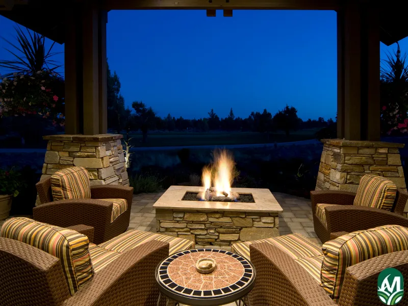 An electric fire pit under a patio at night time.