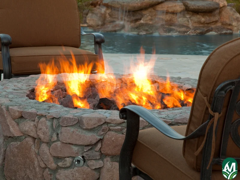 A close-up of two chairs around a burning fire pit. This is for the blog post titled Fire Pit Ideas, Tips for Installation, and Costs.